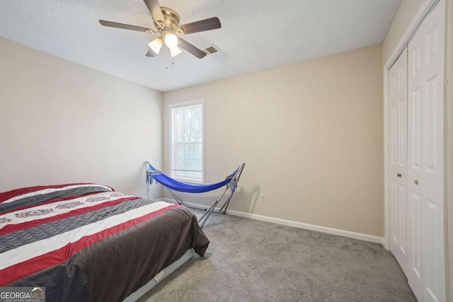 bedroom with a closet, baseboards, a textured ceiling, visible vents, and carpet