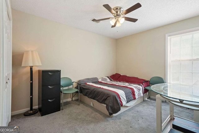 carpeted bedroom featuring a textured ceiling, ceiling fan, and baseboards
