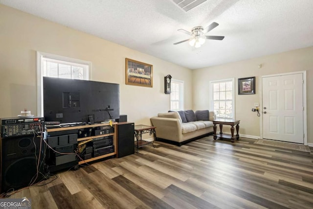 living room featuring visible vents, a ceiling fan, wood finished floors, and a textured ceiling