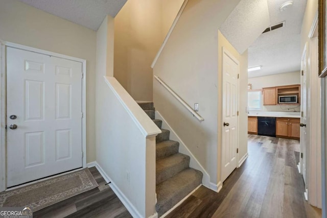 stairs featuring visible vents, baseboards, wood finished floors, and a textured ceiling