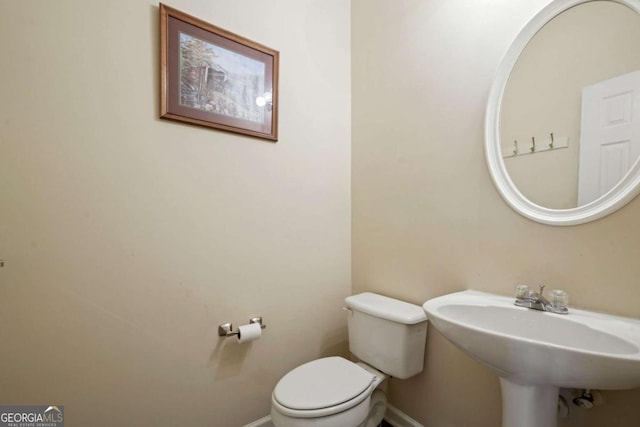 bathroom featuring toilet, a sink, and baseboards