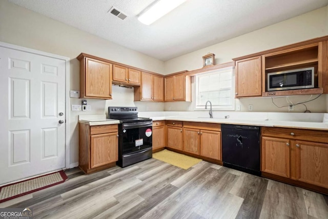 kitchen featuring visible vents, black dishwasher, a sink, electric stove, and stainless steel microwave