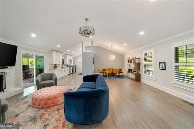 living room featuring baseboards, recessed lighting, crown molding, lofted ceiling, and light wood finished floors