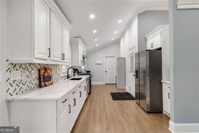 kitchen featuring stainless steel appliances, light wood finished floors, white cabinetry, and vaulted ceiling