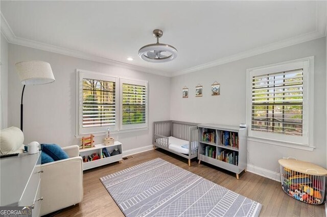 recreation room with wood finished floors, baseboards, and ornamental molding