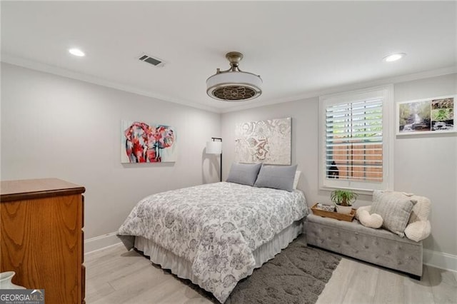 bedroom with ornamental molding, visible vents, light wood-style flooring, and baseboards