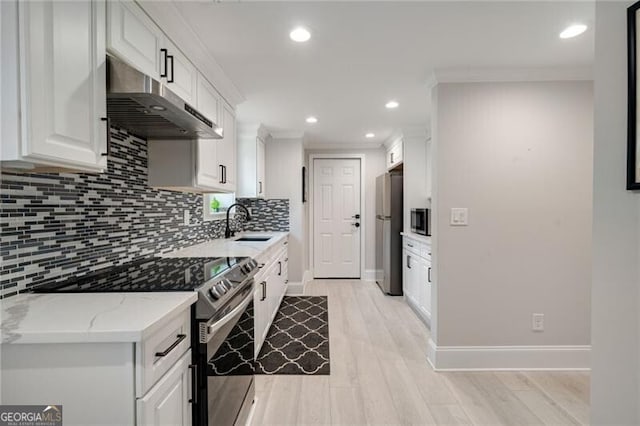 kitchen with freestanding refrigerator, white cabinetry, stainless steel range with electric stovetop, under cabinet range hood, and a sink