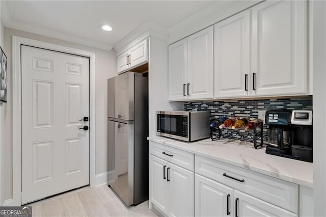 kitchen featuring light stone countertops, white cabinetry, backsplash, and appliances with stainless steel finishes
