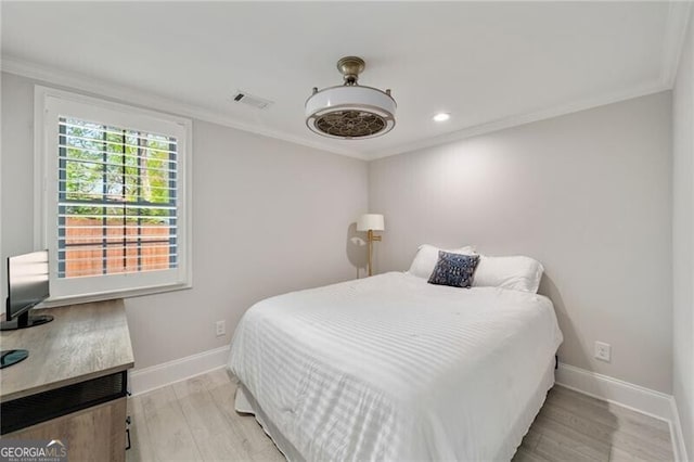 bedroom featuring light wood-style floors, baseboards, ornamental molding, and visible vents