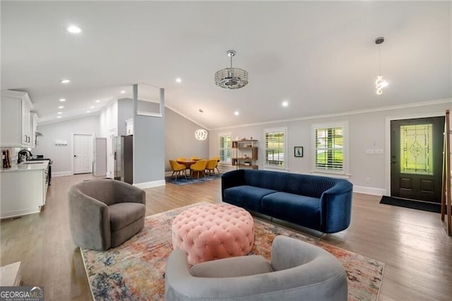 living area featuring light wood-style floors, baseboards, ornamental molding, and lofted ceiling