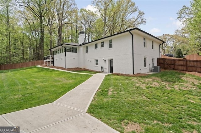 back of house with a yard, cooling unit, fence, and a chimney