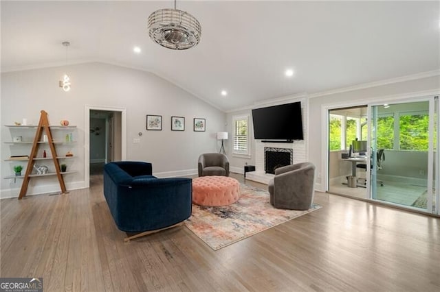 living room with a brick fireplace, baseboards, wood finished floors, and lofted ceiling