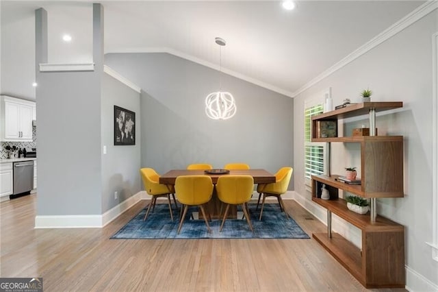 dining area with crown molding, light wood finished floors, a notable chandelier, and lofted ceiling