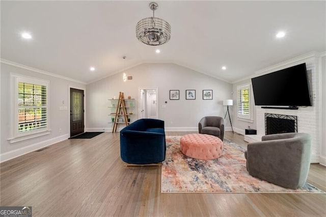living room featuring baseboards, crown molding, a brick fireplace, lofted ceiling, and wood finished floors