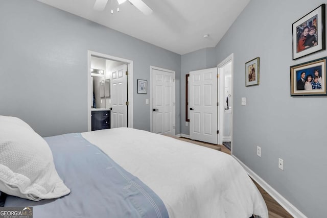 bedroom featuring wood finished floors, ceiling fan, baseboards, and ensuite bath