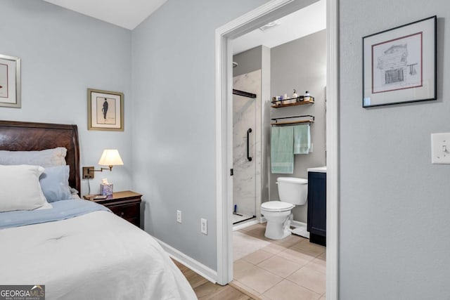 bedroom with light wood-type flooring, baseboards, and ensuite bath