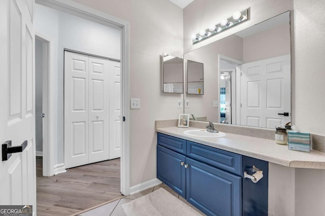 bathroom with wood finished floors, vanity, baseboards, and a closet