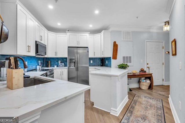 kitchen featuring light wood-style floors, light stone countertops, a peninsula, white cabinets, and appliances with stainless steel finishes