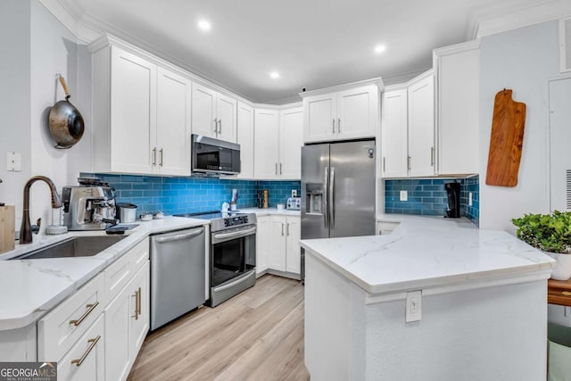 kitchen featuring a peninsula, light wood-style flooring, light stone countertops, stainless steel appliances, and a sink