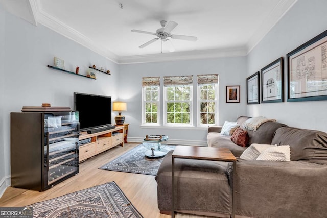 living room featuring ornamental molding, baseboards, light wood finished floors, and a ceiling fan