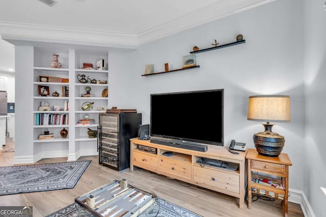 living area with ornamental molding, visible vents, wine cooler, light wood finished floors, and baseboards