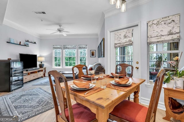 dining space featuring crown molding, a ceiling fan, visible vents, wood finished floors, and baseboards