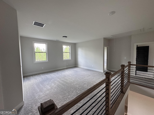 spare room featuring visible vents, attic access, baseboards, and carpet