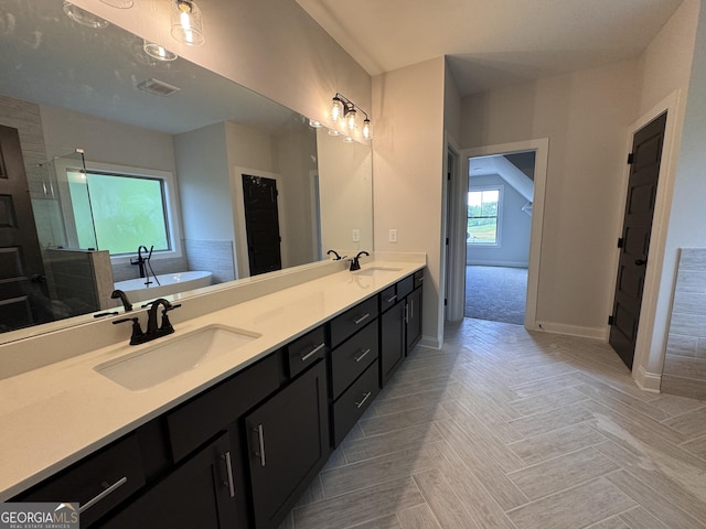 bathroom with baseboards, a tub, a sink, and visible vents