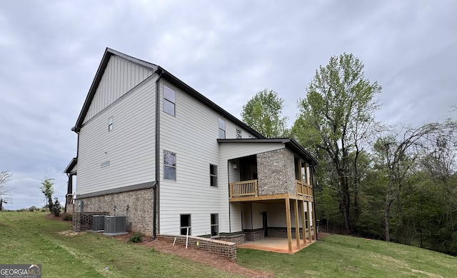 rear view of house featuring brick siding, a patio area, a lawn, a balcony, and board and batten siding