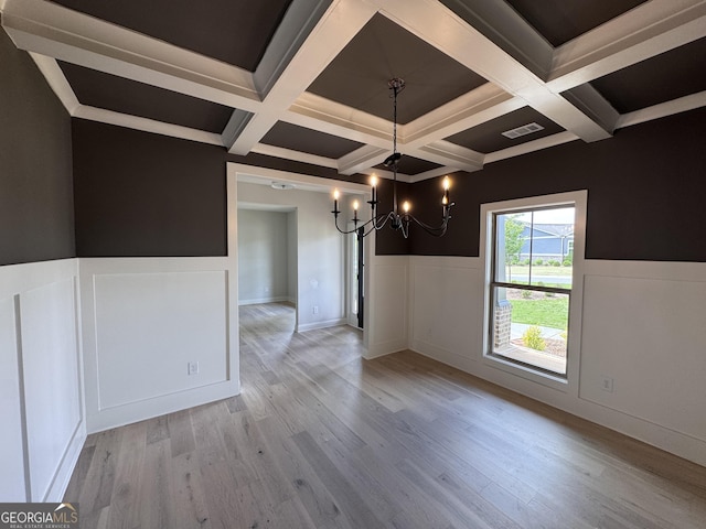 unfurnished dining area featuring coffered ceiling, a wainscoted wall, visible vents, and an inviting chandelier