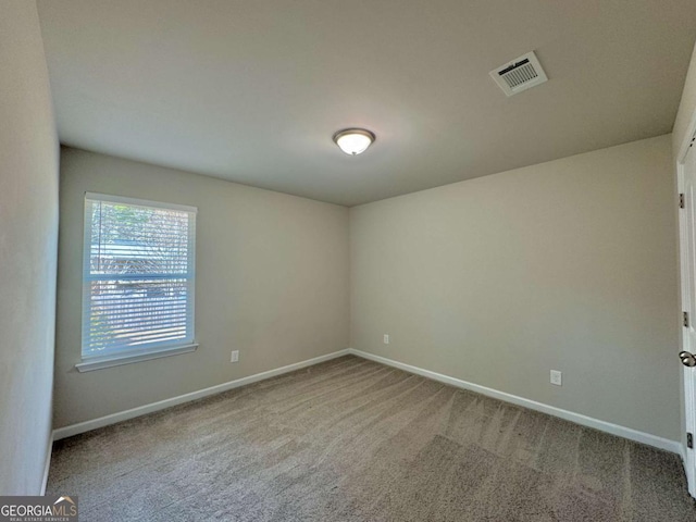 carpeted empty room featuring baseboards and visible vents