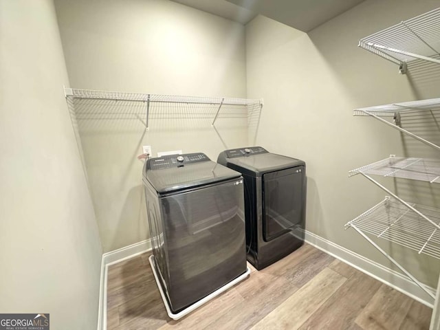 laundry room with laundry area, wood finished floors, baseboards, and washer and clothes dryer