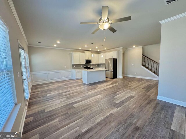 kitchen with open floor plan, appliances with stainless steel finishes, a ceiling fan, and white cabinets