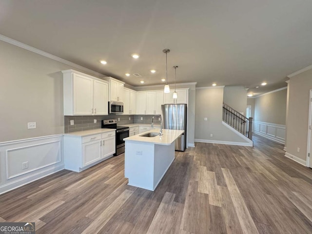 kitchen featuring light countertops, white cabinets, decorative backsplash, stainless steel appliances, and a sink