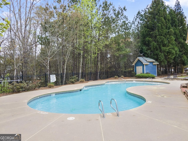 pool featuring a patio area, fence, and an outdoor structure