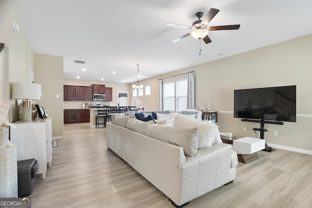 living room with recessed lighting, visible vents, ceiling fan with notable chandelier, and light wood-style flooring
