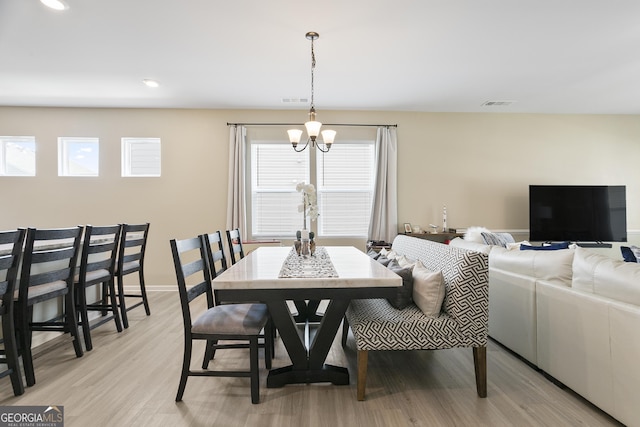 dining area with baseboards, light wood-style floors, a notable chandelier, and visible vents