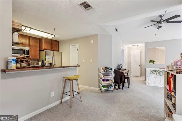 kitchen featuring light carpet, a ceiling fan, visible vents, brown cabinetry, and stainless steel appliances