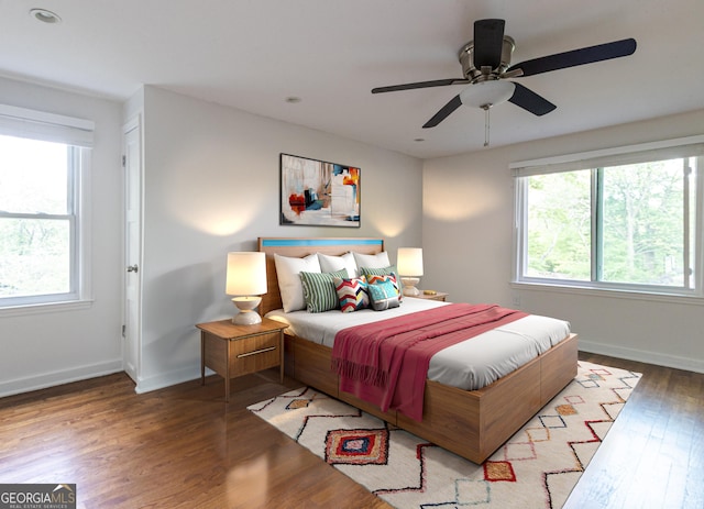 bedroom with baseboards, wood finished floors, and multiple windows