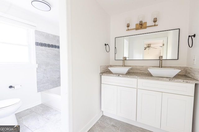 full bath featuring double vanity, toilet, baseboards, and a sink