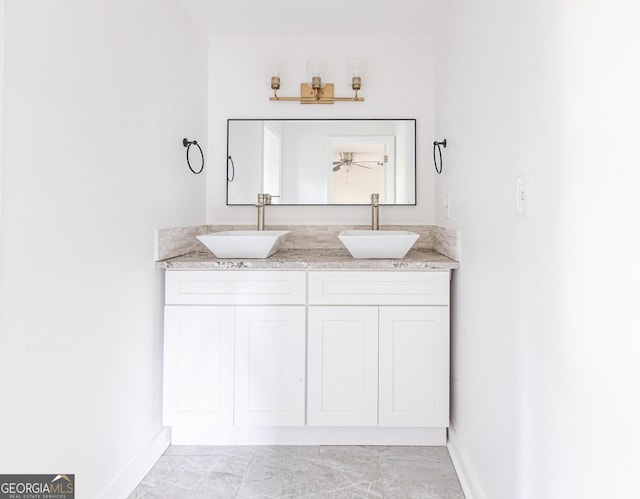 bathroom featuring ceiling fan, baseboards, a sink, and double vanity