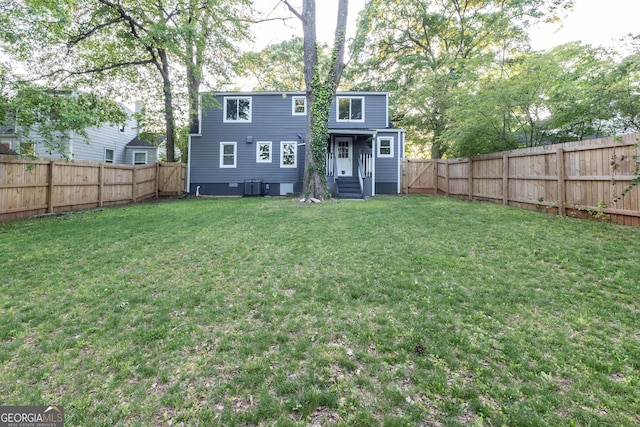 rear view of house featuring a fenced backyard, a yard, entry steps, and central AC