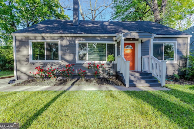 bungalow-style home featuring a shingled roof, a chimney, and a front yard