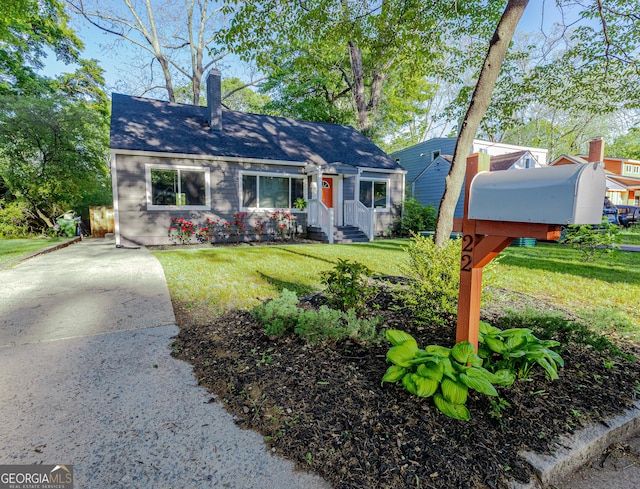 view of front of property with a shingled roof, a front lawn, and a chimney