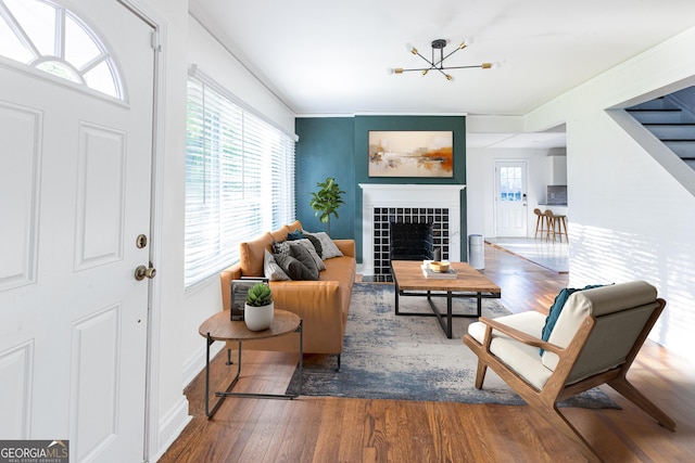 living room with a tile fireplace, baseboards, a chandelier, and wood finished floors