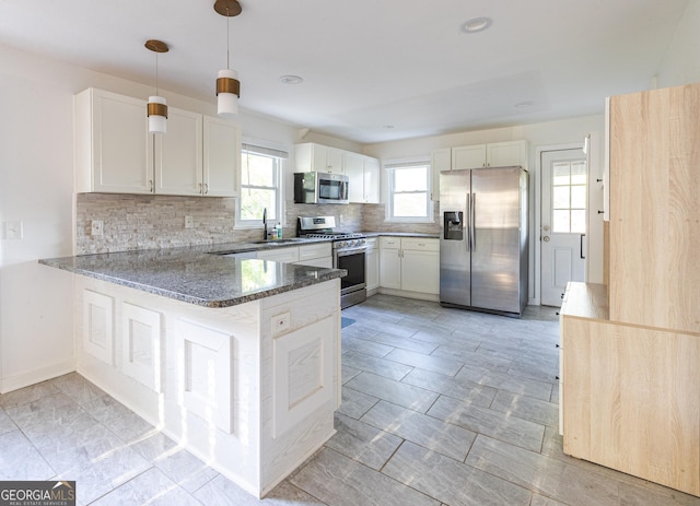 kitchen featuring white cabinets, stone countertops, decorative backsplash, a peninsula, and appliances with stainless steel finishes