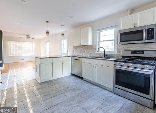 kitchen with stone counters, stainless steel appliances, a peninsula, and a sink