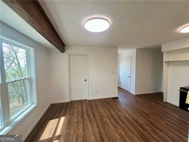 interior space featuring a textured ceiling, wood finished floors, beamed ceiling, and baseboards