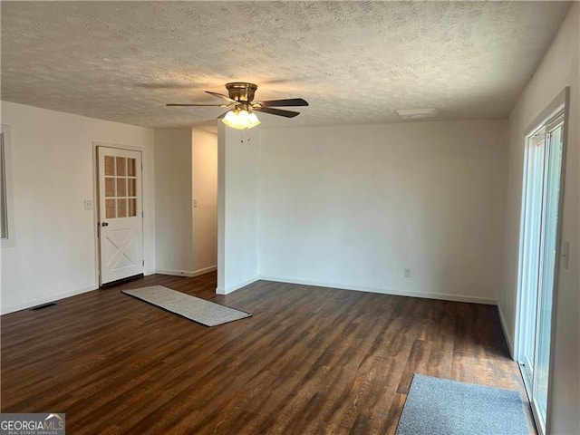 empty room featuring a ceiling fan, a textured ceiling, dark wood-style floors, and visible vents