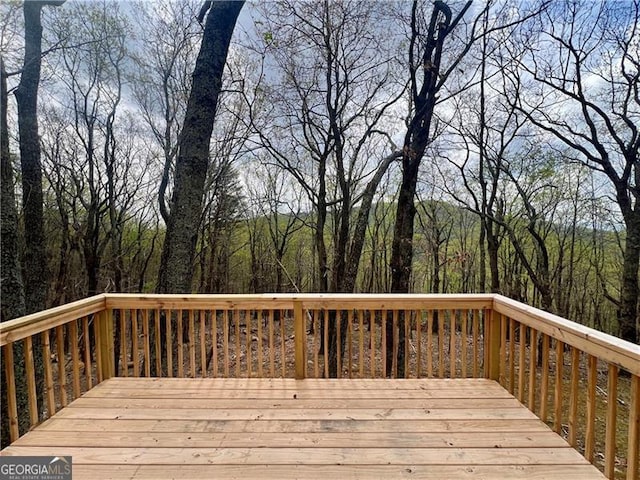 wooden terrace featuring a view of trees